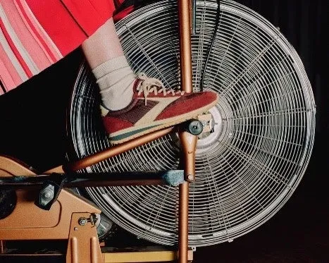 扇風機の上に足を乗せた自転車のペダルを踏む人の写真。