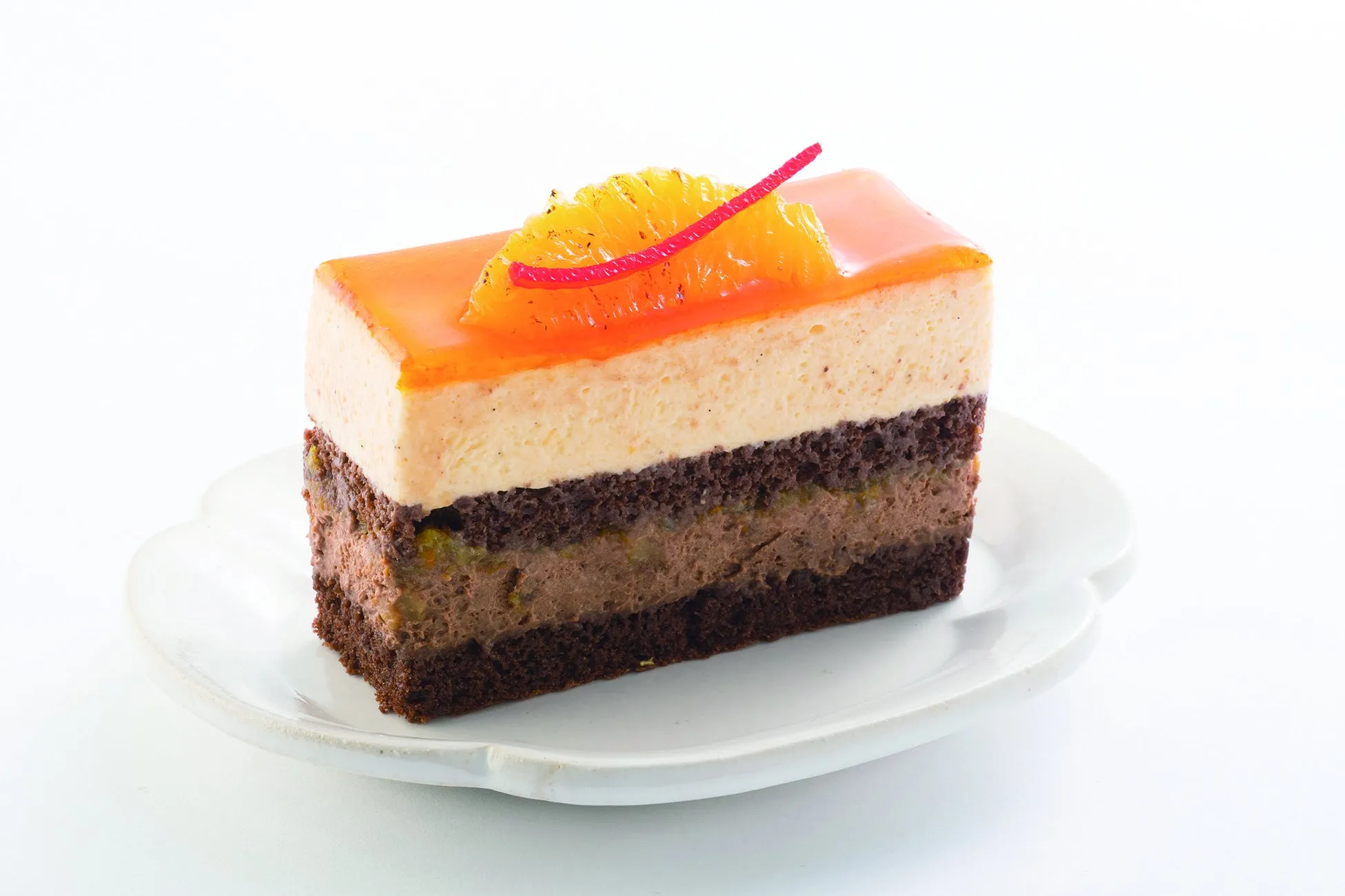 オレンジと赤い飾りで飾られた、白い皿に載った美味しそうなケーキ