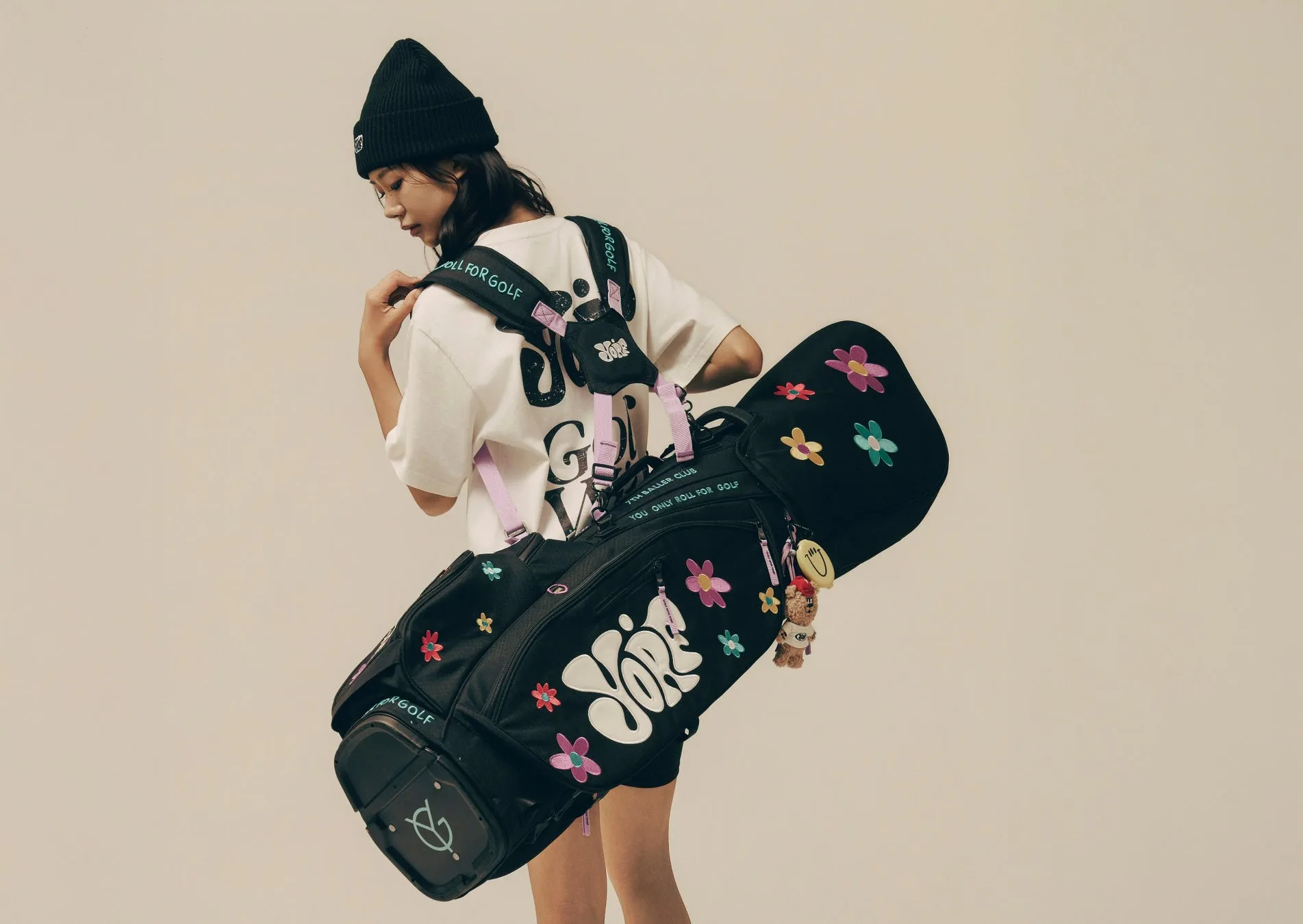 黒い帽子をかぶり、ゴルフバッグを背負った女性の画像