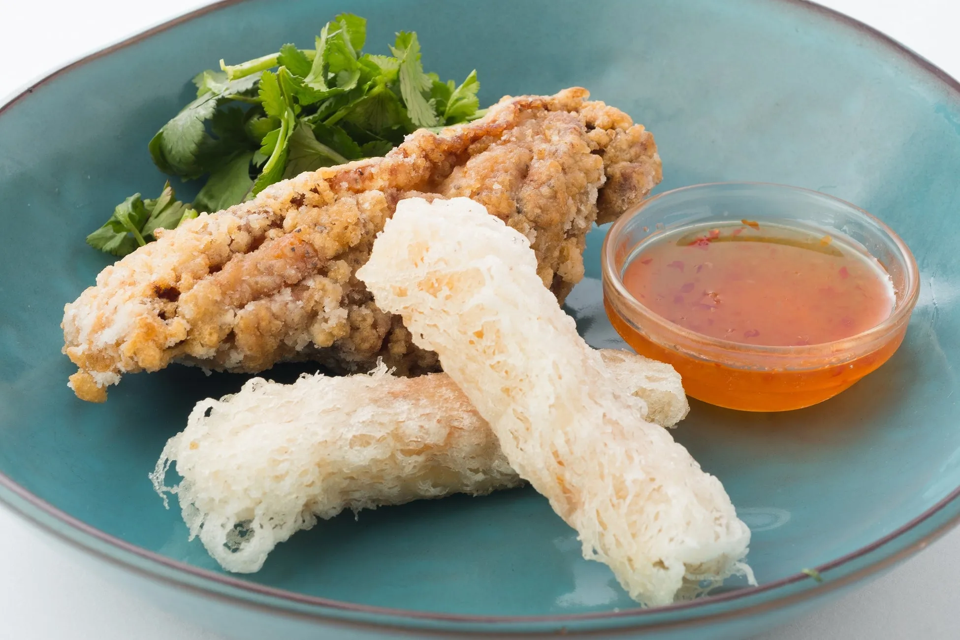 青い皿の上に、揚げ物、ソース、パクチー