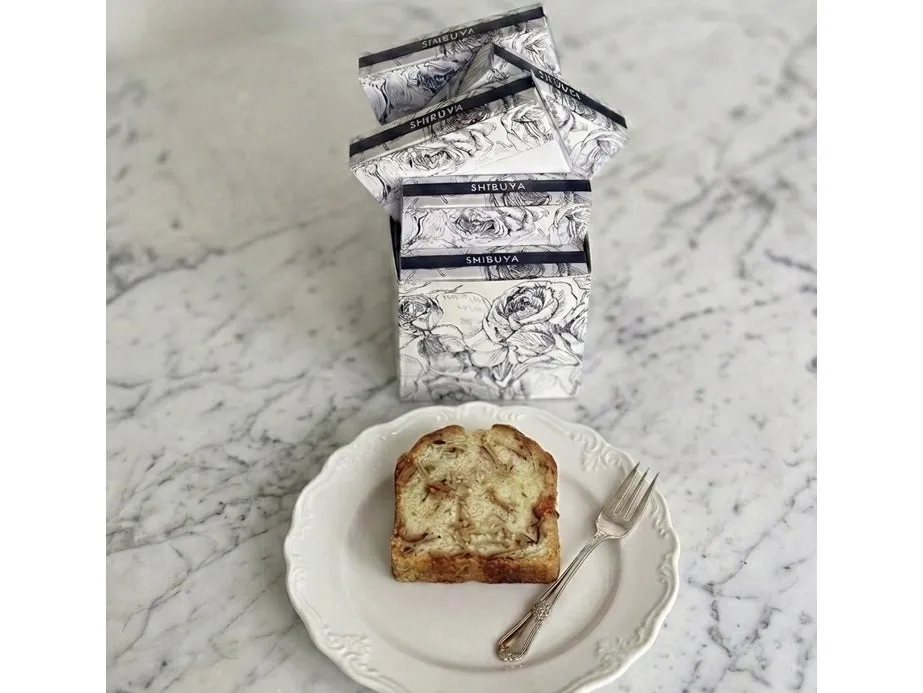 白い皿にパンとフォークが置かれ、積み重ねられた箱の上にはSHIBUYAの文字が書かれています