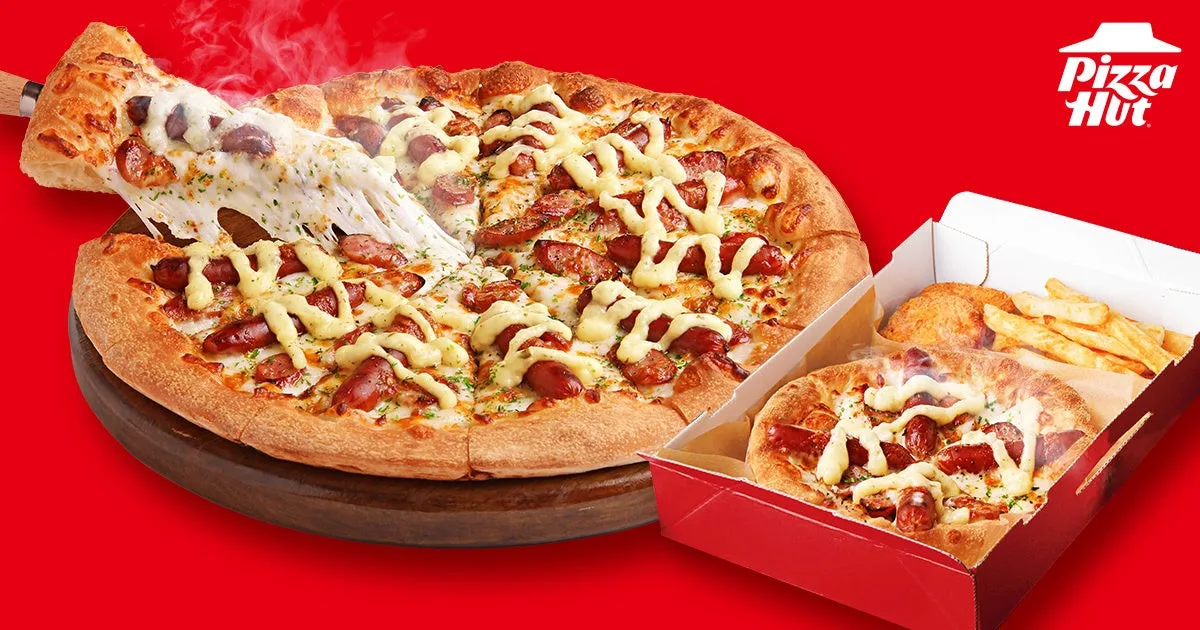 ピザハットのソーセージピザの画像です。ピザが木製の台に置かれ、チーズがとろけています。ピザの箱には、小さいピザ、フライドポテト、揚げ物が入っています。