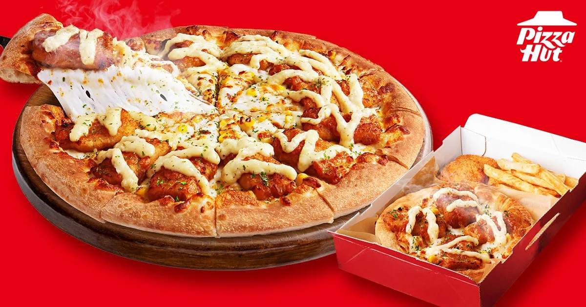 ピザハットのピザの画像。ピザはチーズとトッピングがたっぷり。ピザが箱から取り出され、チーズが伸びている様子が写っている。箱の中には、フライドポテトと丸い食べ物も入っている。
