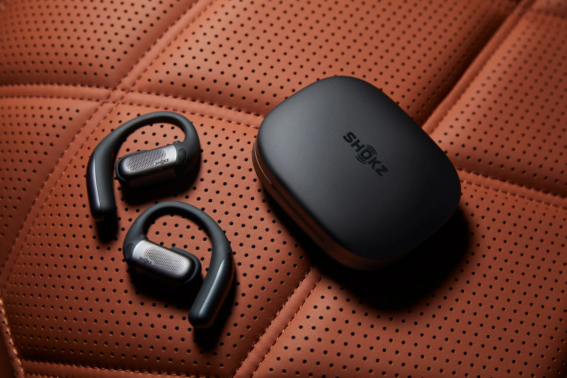Shokzのイヤホンとケースが革張りの上に置かれている写真です。