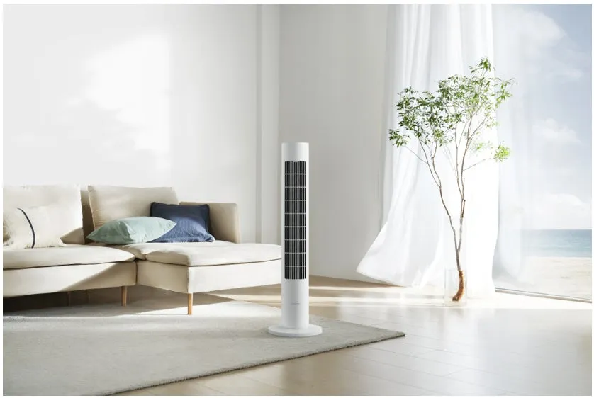 リビングルームの様子。白いタワーファンが置かれ、ソファとラグが配置されている。窓からは海が見える。