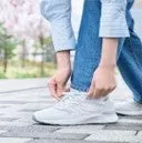 白いスニーカーの靴紐を結んでいる人の手元のクローズアップ