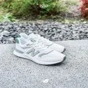 白いニューバランスのスニーカーがグレーの砂利の上に置かれている