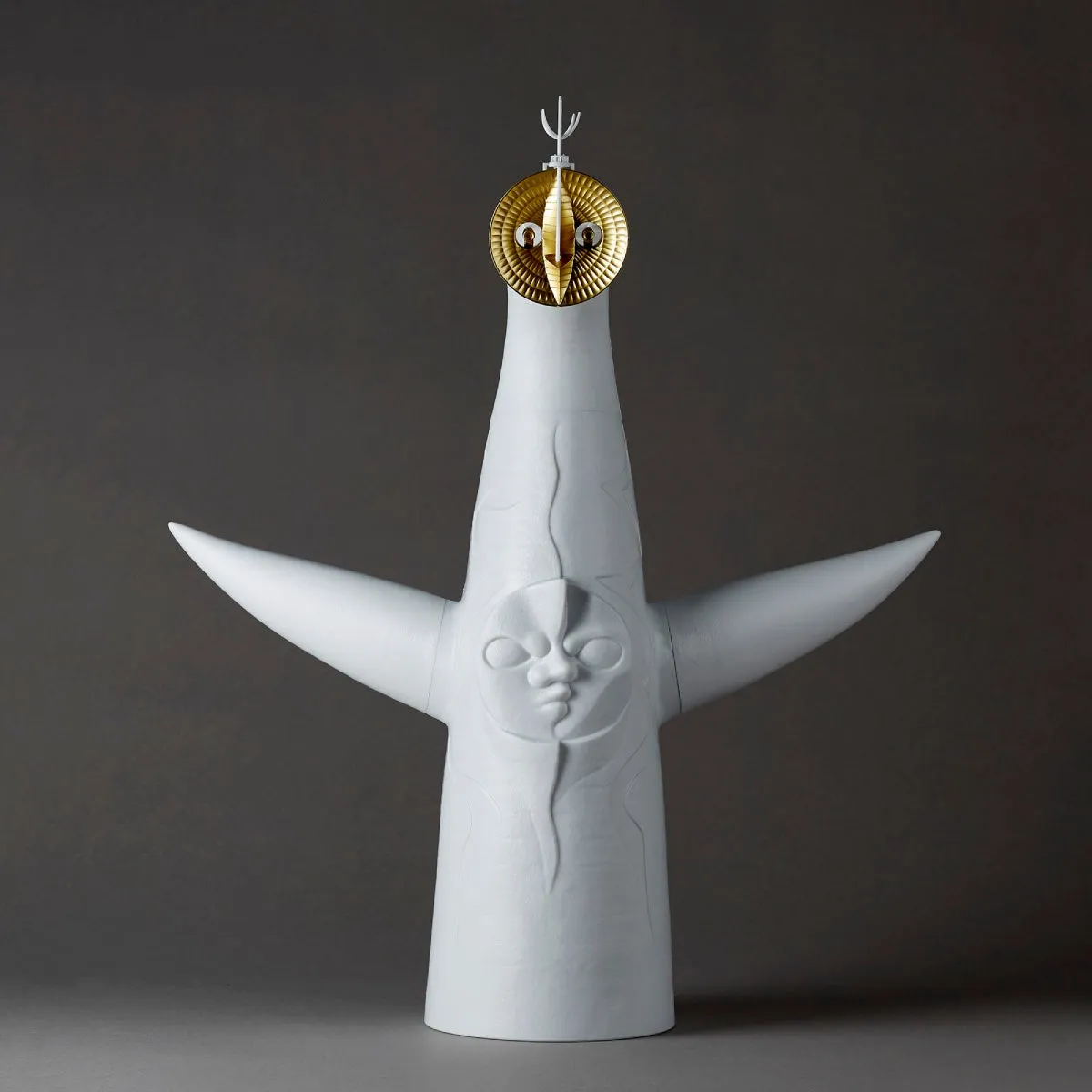 白いオブジェ。顔と腕があり、頭には金色の飾りがついている。