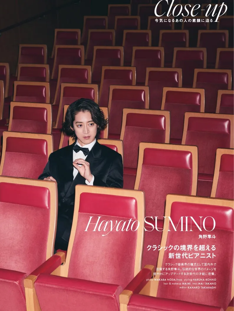 クラシック音楽界のピアニスト、角野隼斗の雑誌の表紙。赤い座席に座り、スーツに蝶ネクタイ姿でカメラを見つめている。