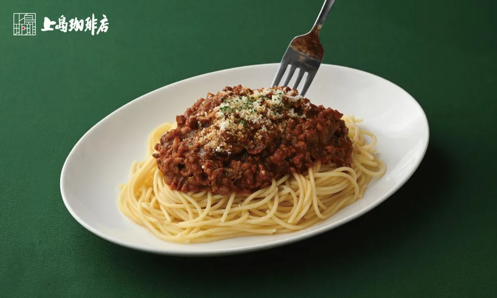 お皿に盛られたミートソースパスタの写真。フォークが刺さっている。