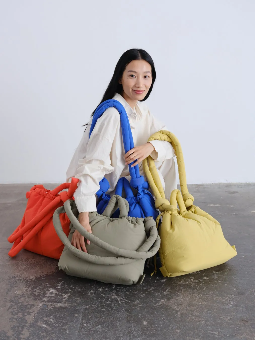 女性が複数の色のバッグを持って座っている写真