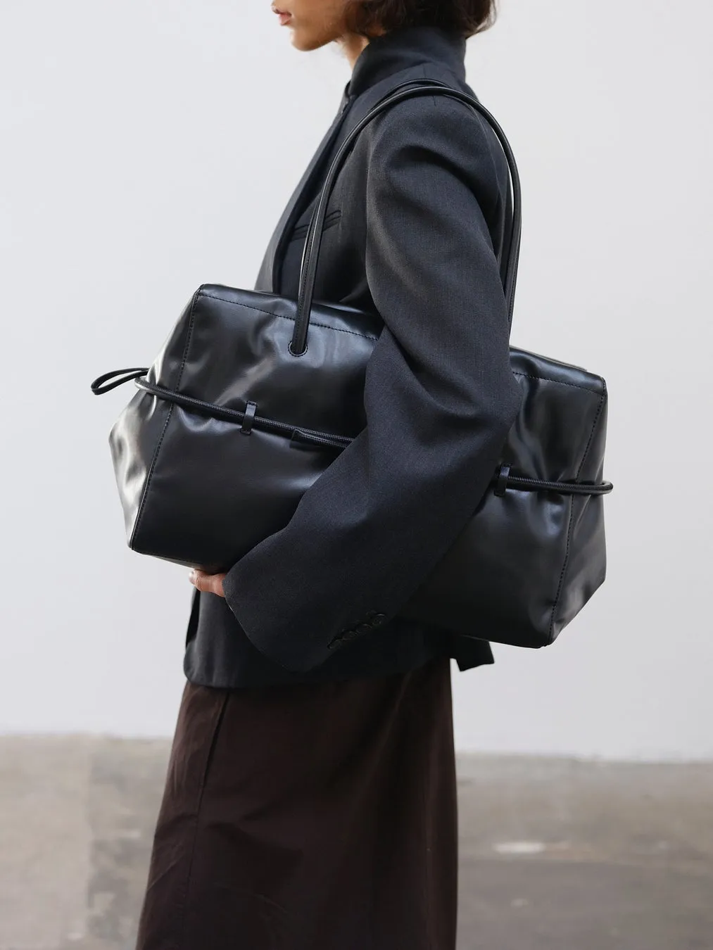 黒い革のバッグを肩にかけた女性