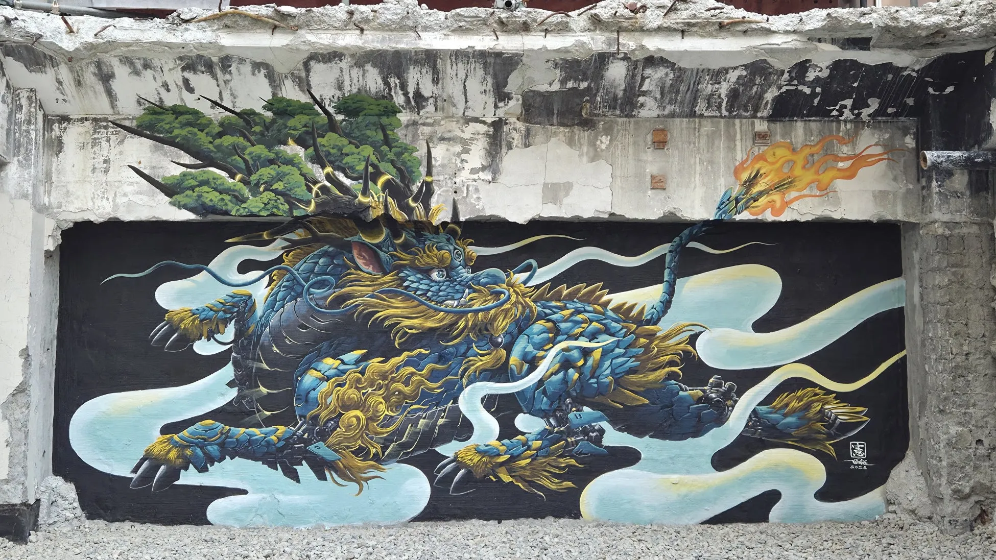壁に描かれた青と金の龍の壁画。龍は大きく、今にも動き出しそうな姿で描かれている。背景は黒で、白い雲のような模様が描かれている。龍の周りには炎のようなものが描かれ、迫力ある印象を与えている。