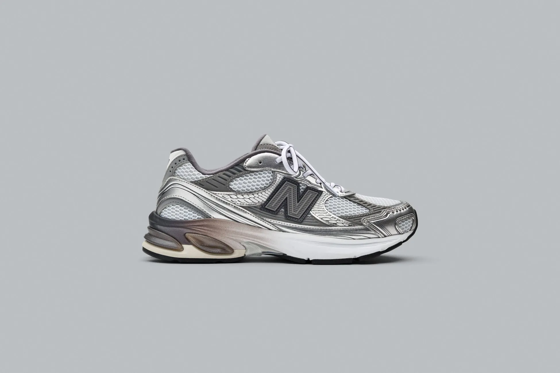 ニューバランスのスニーカーが、グレーの背景に配置されています。