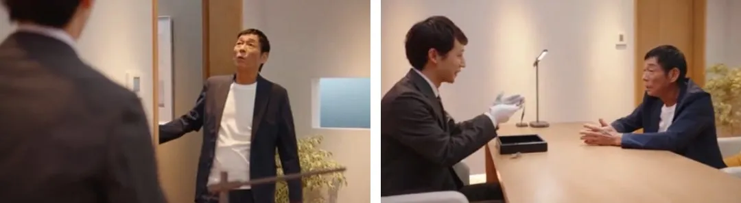 室内で会話する男性たち。一人はドアを開けようとしており、もう一人はテーブルに座っている。