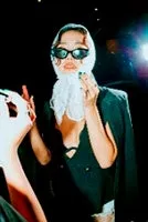 サングラスとスカーフを身につけた女性がポーズをとっている写真です。