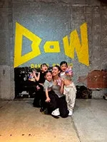 壁にD-Wと書かれたロゴがある場所で、女性と子供たちがポーズをとっている写真です。