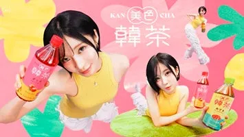 女性がイチゴ風味のドリンクのボトルを持ってポーズをとっている鮮やかな広告画像です。背景には、黄色と緑の抽象的な要素と、ドリンクボトルの他の画像が含まれています。
