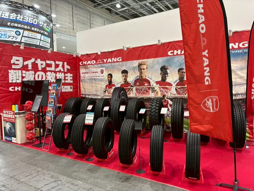 タイヤの展示会。CHAOYANGのタイヤと、アーセナルのロゴが入った旗が立っている。タイヤの展示台には、様々な種類のタイヤが並べられている。