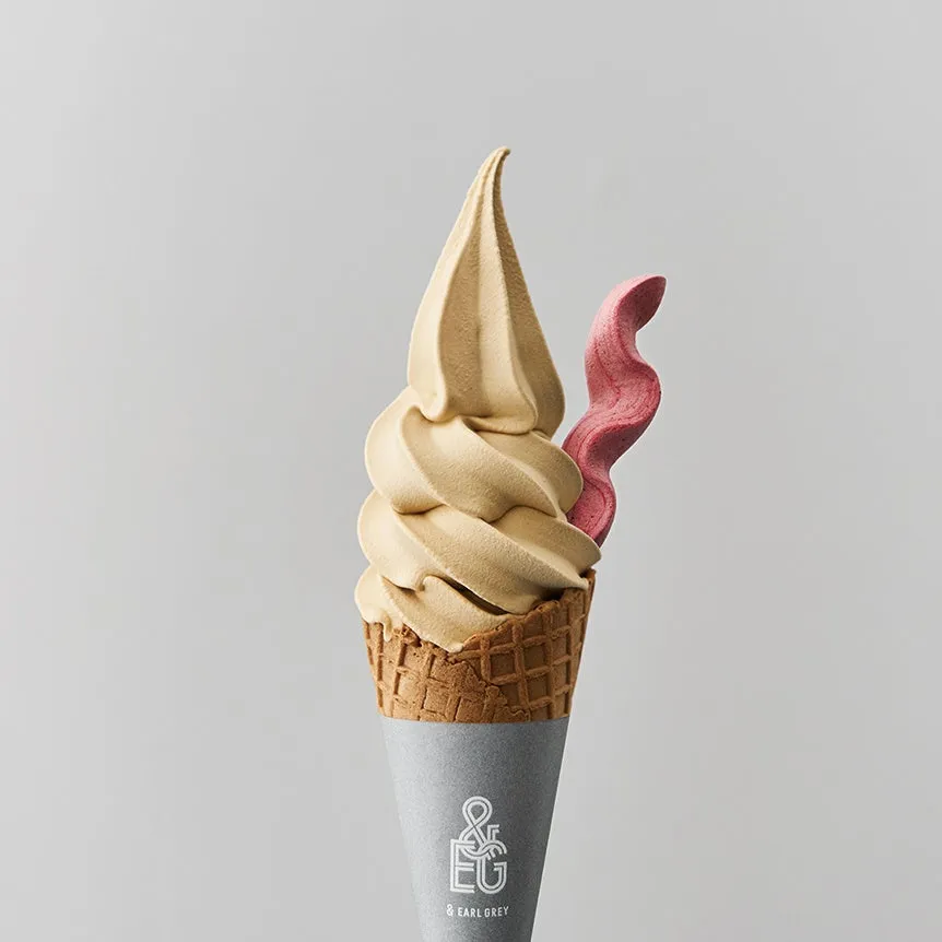 コーンに盛られたソフトクリーム。茶色いソフトクリームと、ピンク色のトッピングが添えられている。