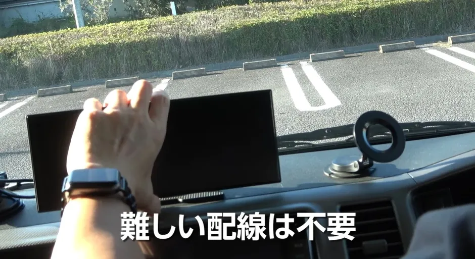 車内でモニターを手に持っている様子。モニターの取り付けに難しい配線は不要というメッセージが表示されています。