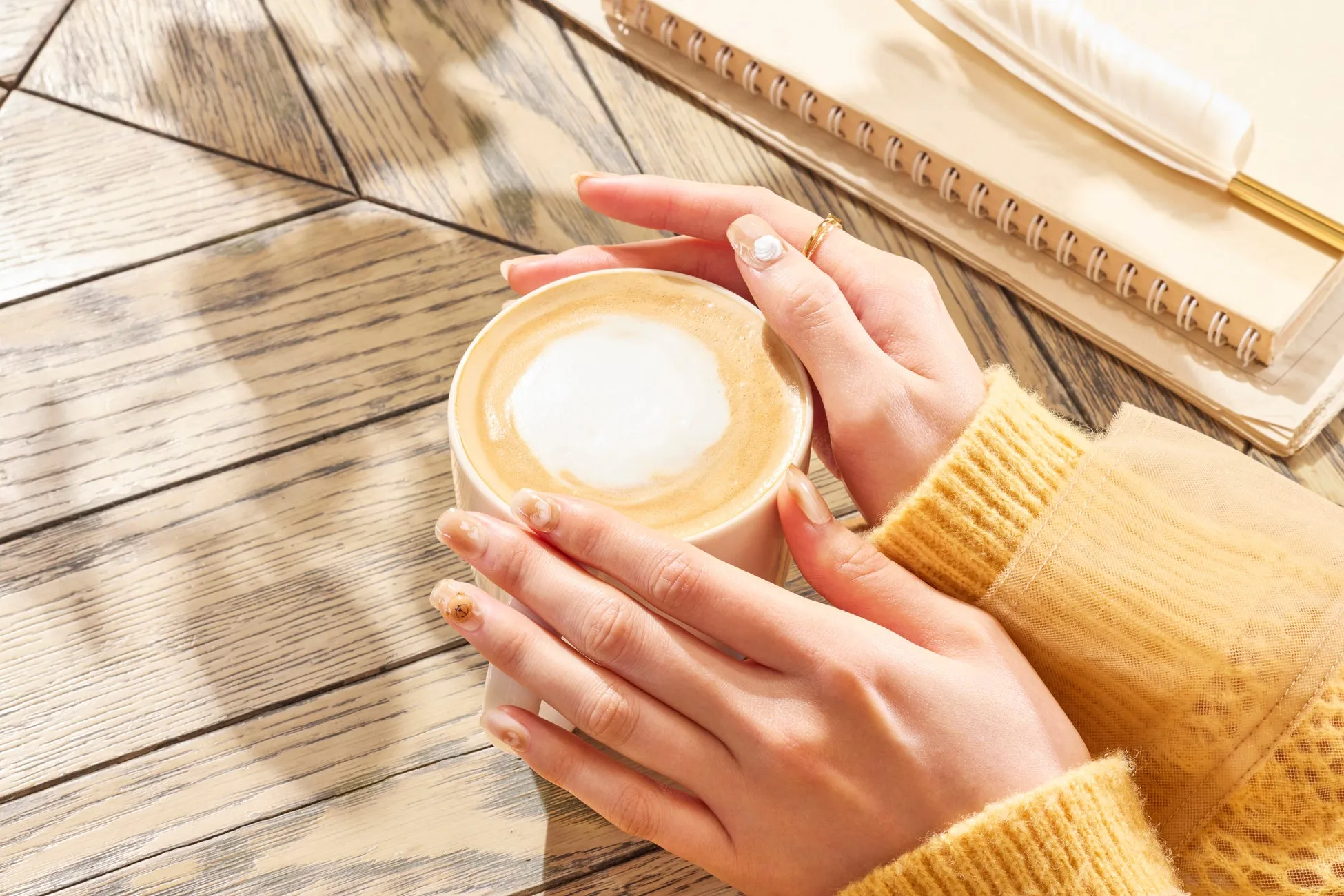 カフェラテを手で持っている様子が写っています
