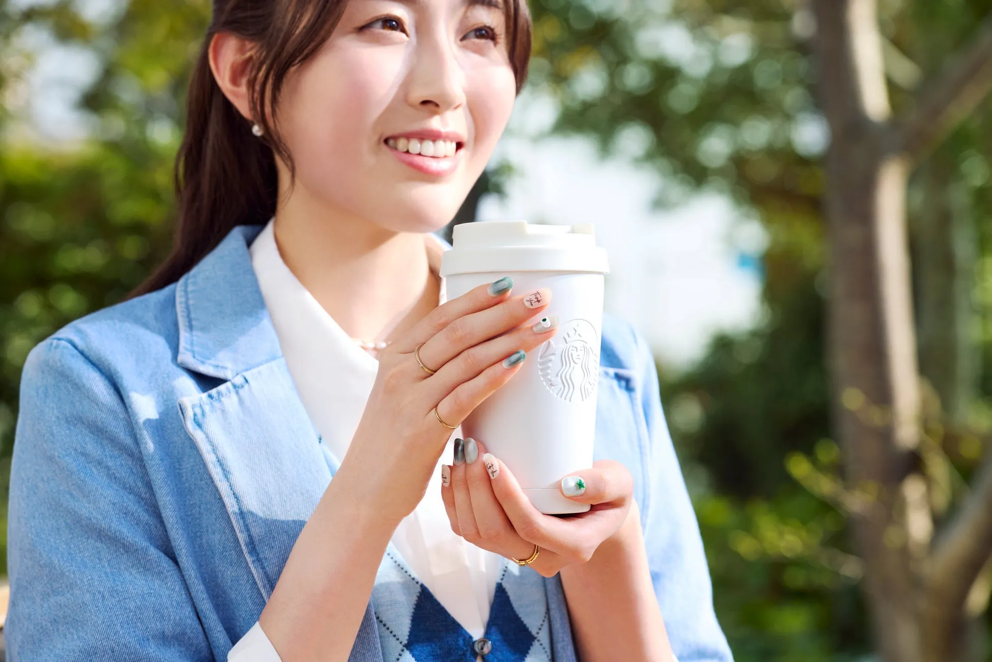 若い女性が屋外でコーヒーカップを持っています
