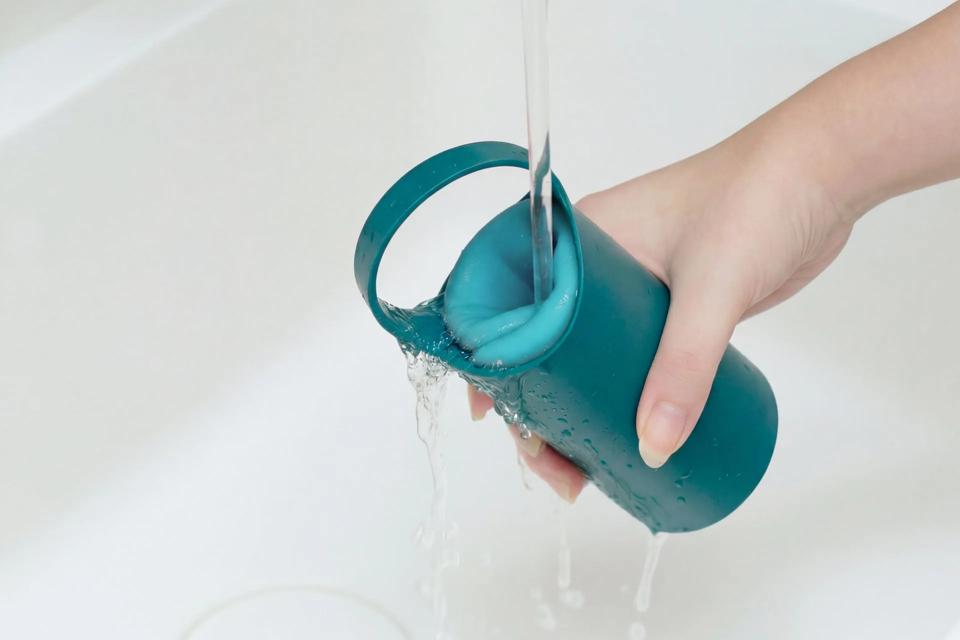手で持った青い容器に水が流れ込んでいる様子