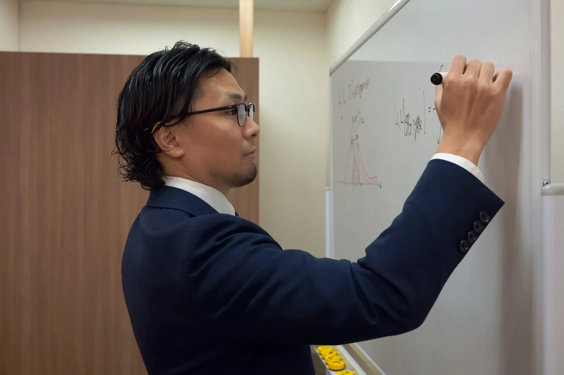 ホワイトボードに数式を書く男性