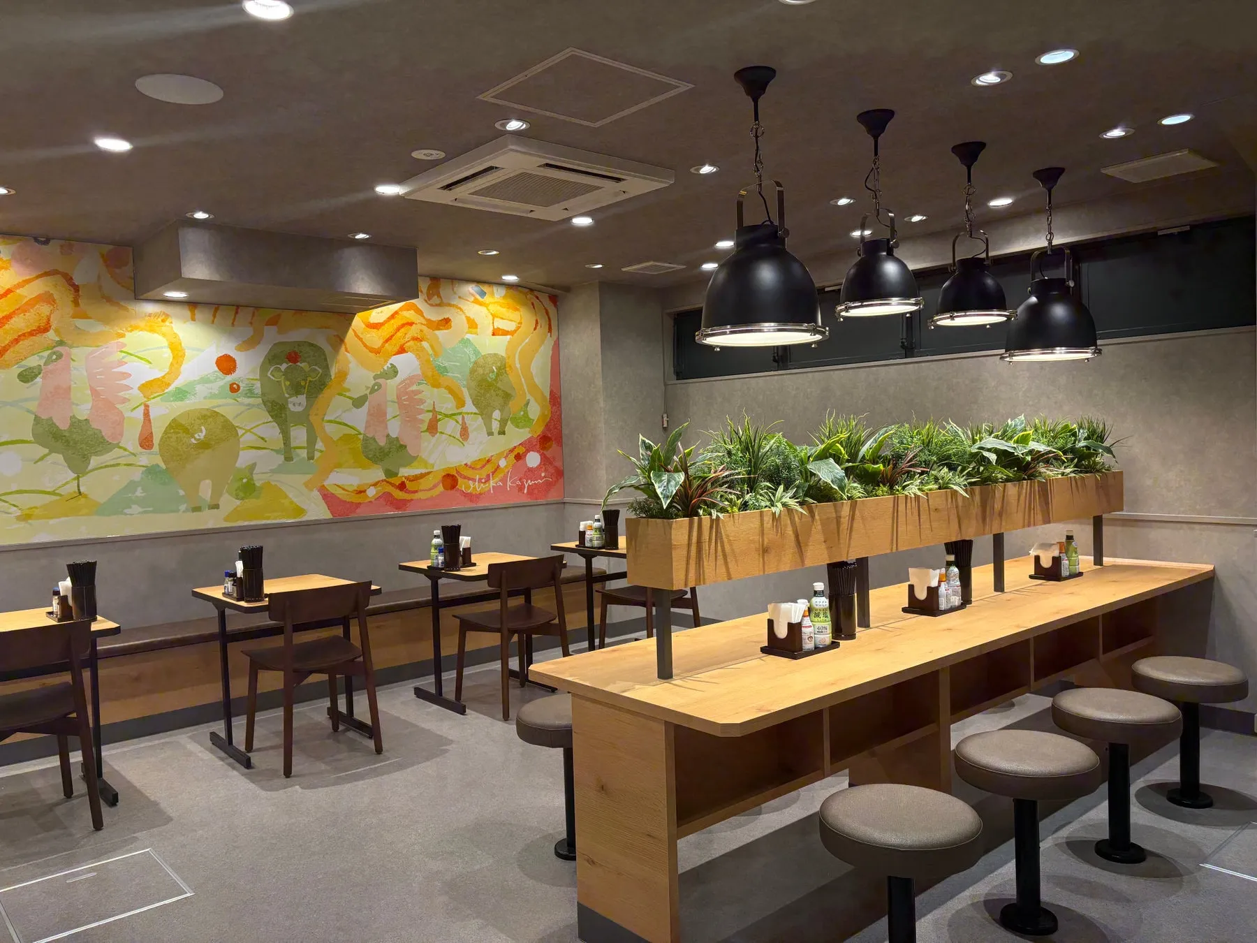 店内。カウンター席とテーブル席があり、壁には絵が飾られている。照明がおしゃれ。