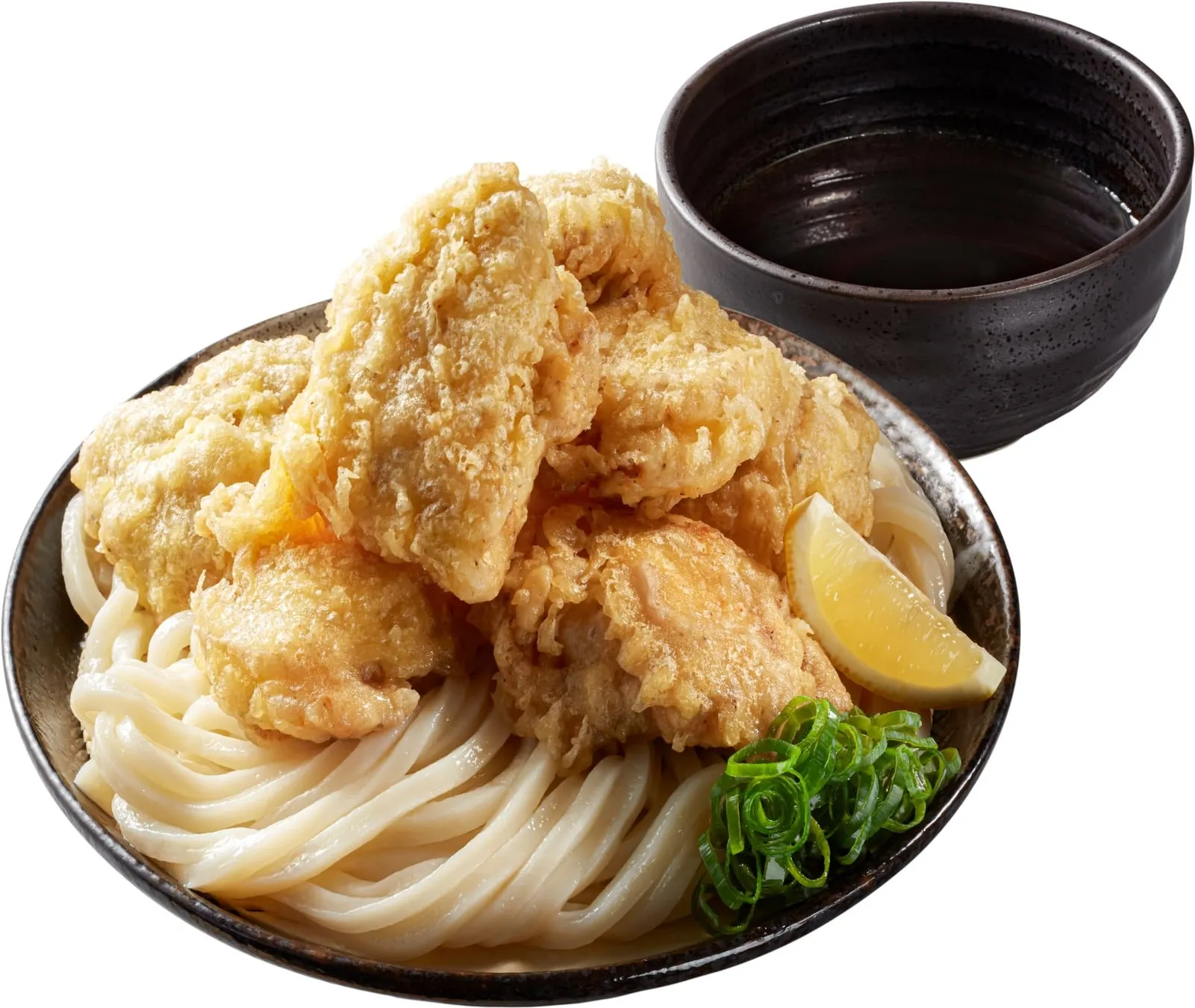 うどんに揚げ物が乗った料理の写真です。ネギとレモンが添えられています。