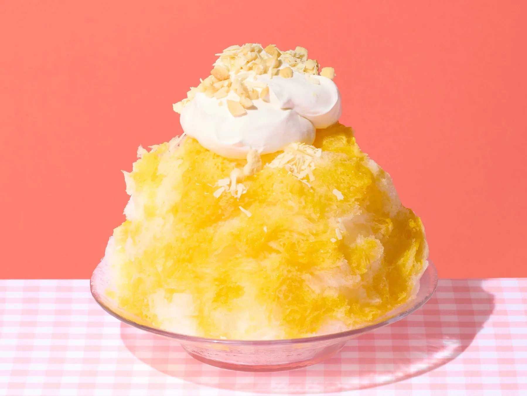かき氷の上にホイップクリームとナッツがトッピングされた写真。