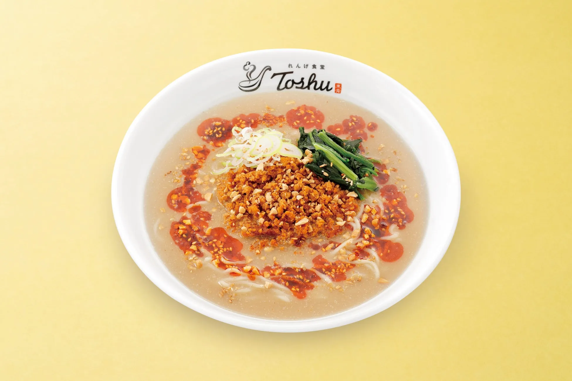 白いラーメン丼に盛られたラーメンの画像。ラーメンは、スープ、麺、トッピングで構成されています。トッピングには、刻みネギ、ほうれん草、ひき肉のようなもの、ラー油のようなものが見えます。背景は黄色です。
