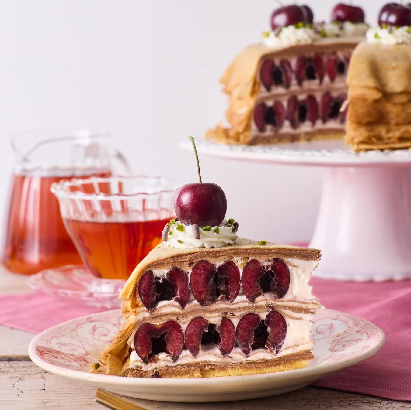 チェリーが挟まれたケーキと、飲み物とケーキが置かれた様子を写した写真です。
