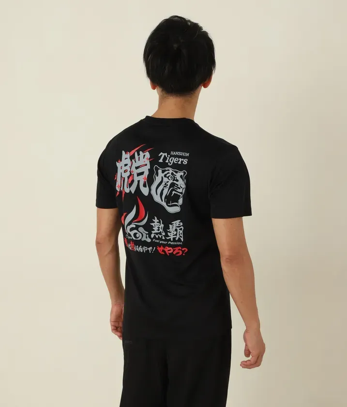黒いTシャツを着た男性の後ろ姿。Tシャツには阪神タイガースのロゴと文字がプリントされている。