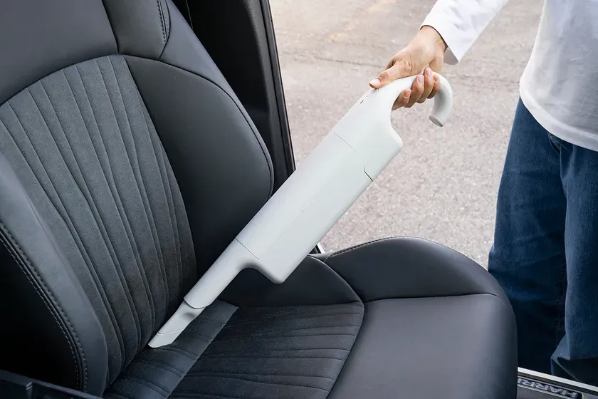 車のシートを掃除機で掃除している様子。