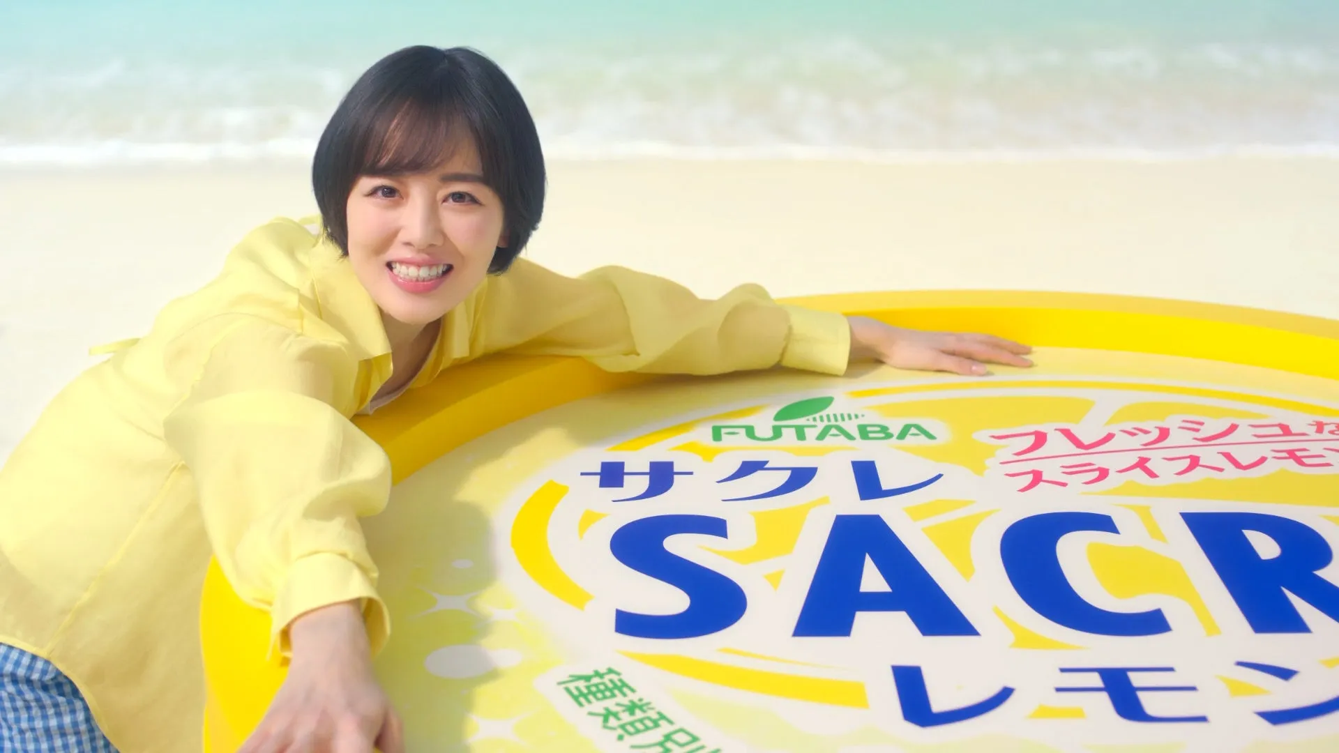 浜辺で女性がサクレレモンの商品に寄り添い、笑顔を見せている様子