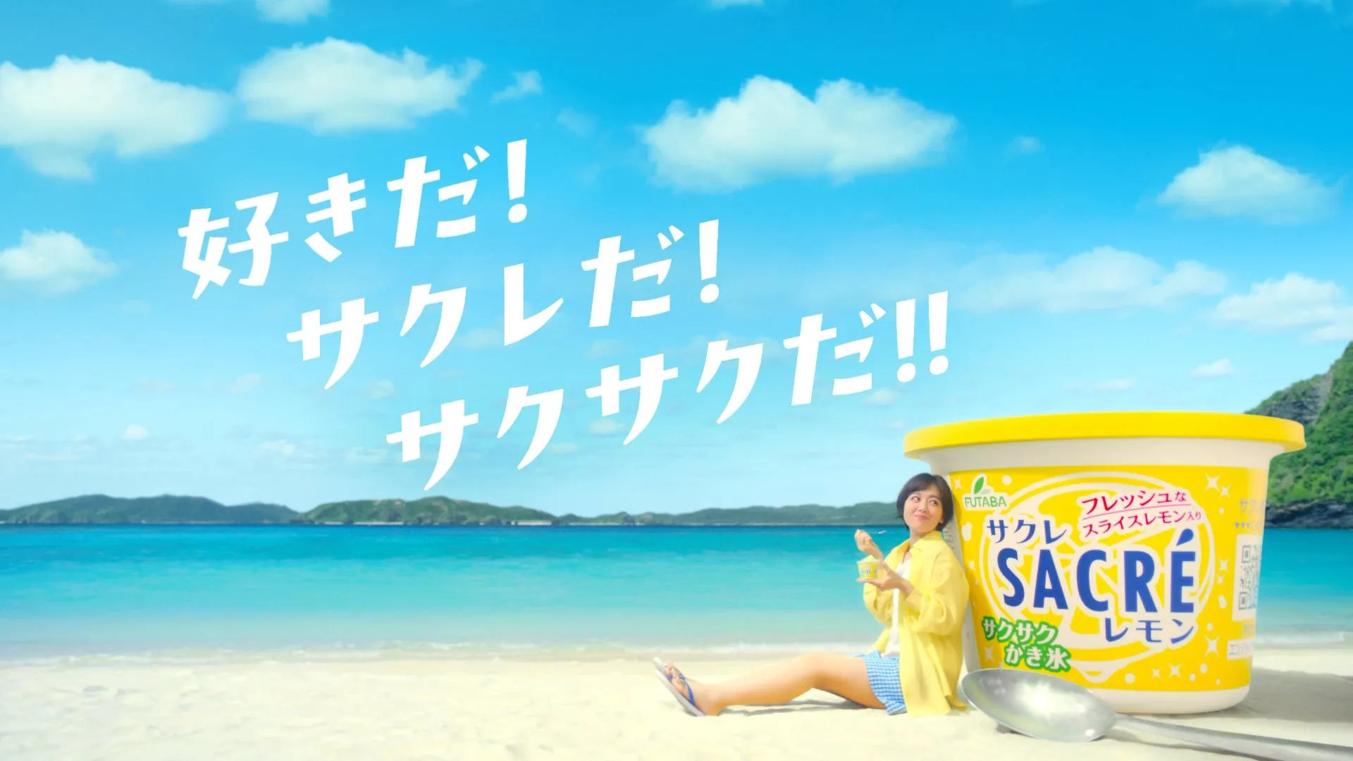 ビーチで女性がサクレレモンのかき氷を食べている広告画像。空には「好きだ！サクレだ！サクサクだ！！」の文字が書かれている。