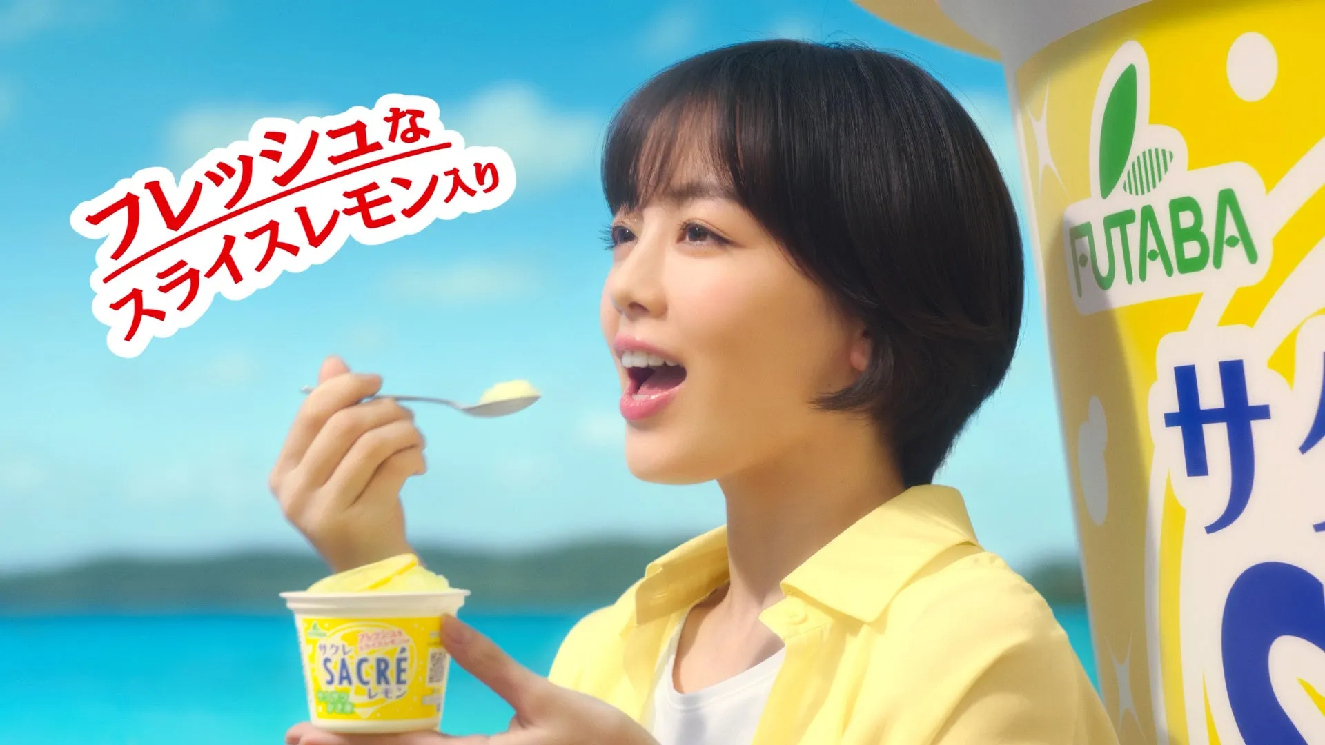 女性がsacréレモンのアイスを食べている様子。背景には海と空が広がり、爽やかな印象を与える。