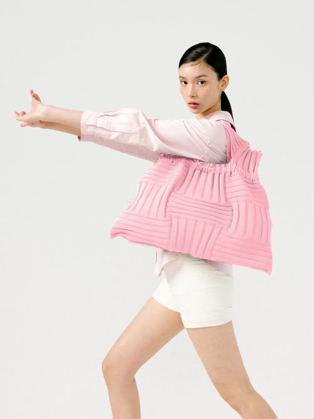 ピンク色のバッグを持った女性がポーズをとっている様子。
