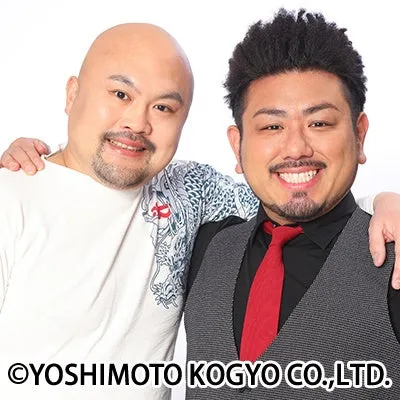 スキンヘッドと黒髪の男性芸人2人が笑顔でポーズをとっている。