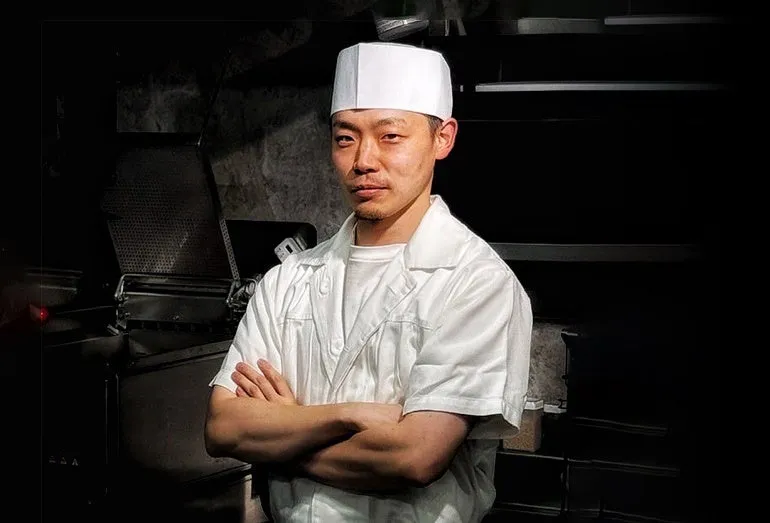 料理人が腕組みをして立っている写真