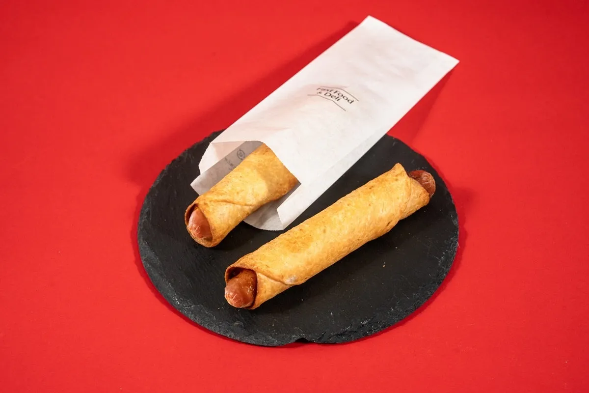 ホットドッグを包んだ料理が、黒いお皿の上に置かれています。