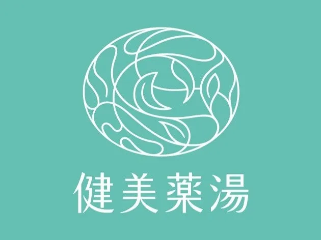 水色の背景に、白い線で描かれた楕円形の模様と「健美薬湯」という文字が配置された画像。
