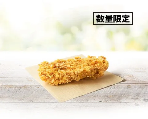 揚げ物の写真です。揚げ物は茶色の紙の上に置かれています。背景は木製のテーブルとぼやけた緑色の背景です。