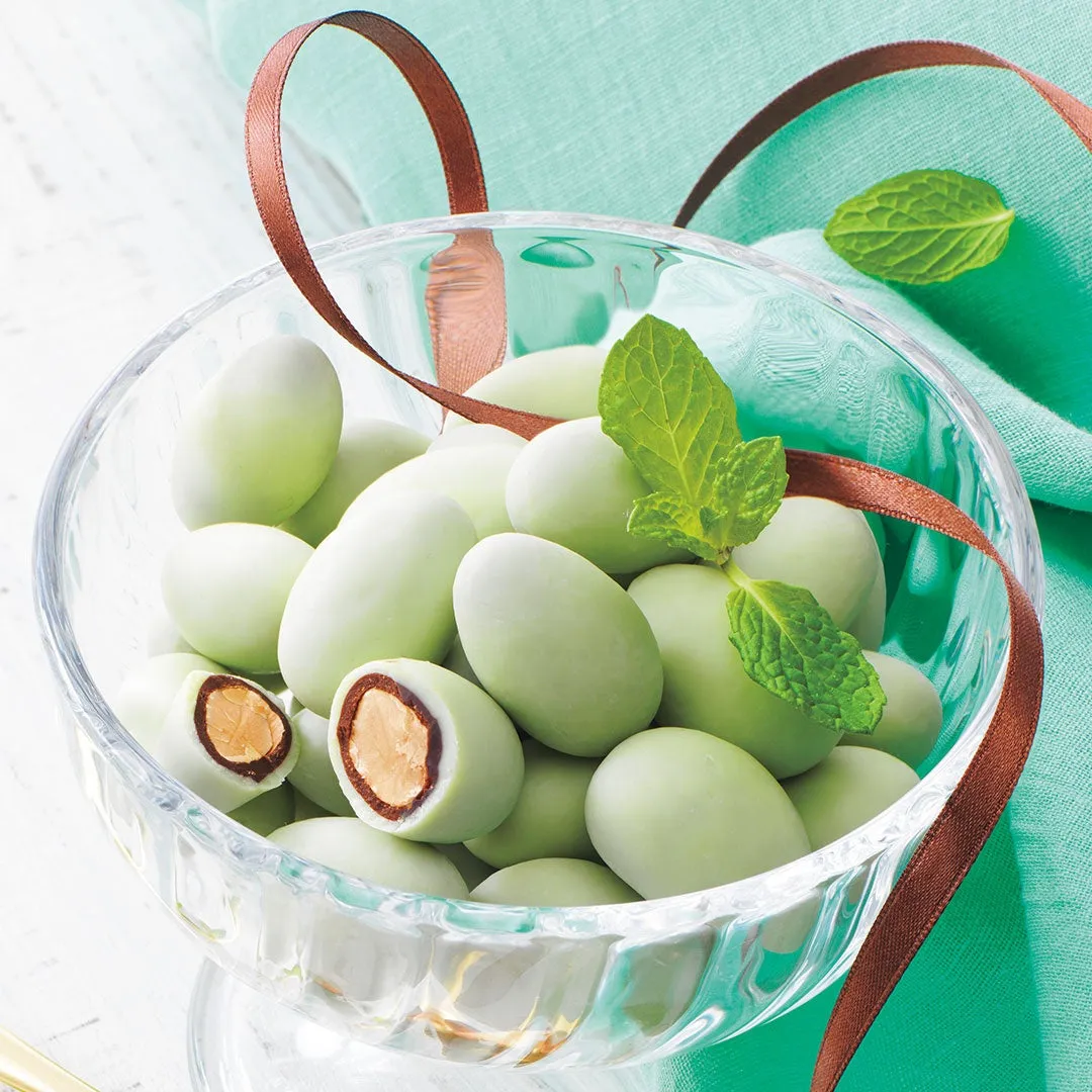 ガラスの器に入った、緑色のチョコレートでコーティングされたアーモンドのお菓子。