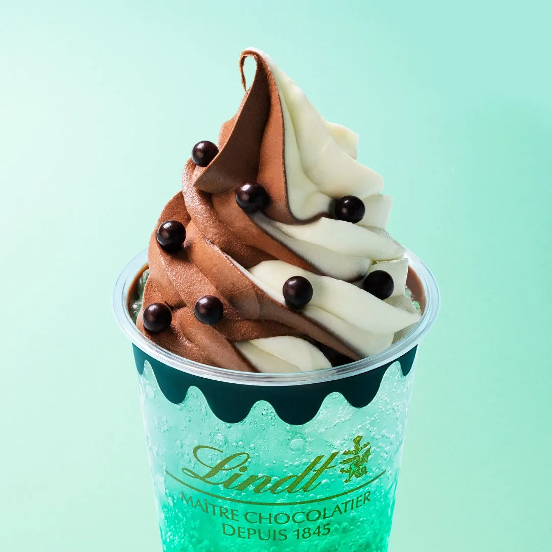 リンツのソフトクリームとソーダのデザートの画像です。チョコレートとバニラのソフトクリームにチョコレートボールがトッピングされています。ソーダはミント色で、リンツのロゴが描かれたカップに入っています。