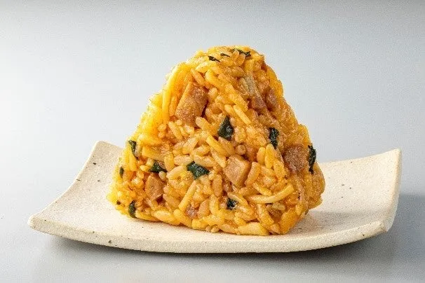 おにぎりが白いお皿に置かれています。おにぎりは三角形で、ご飯、野菜、肉など様々な具材が混ざっています。
