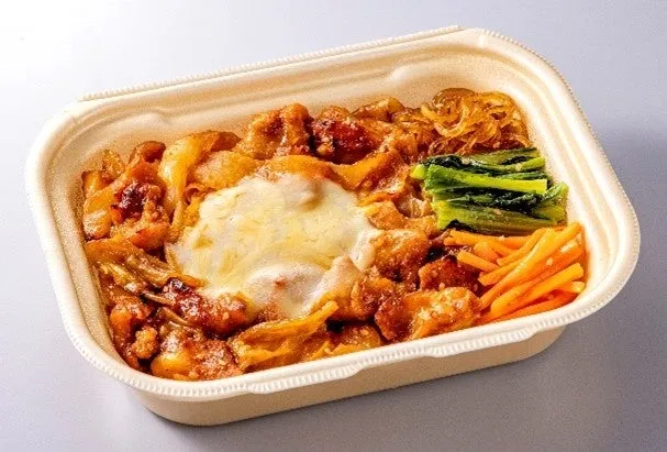 弁当箱に入った料理。チーズが乗った鶏肉、野菜、麺などが含まれています。
