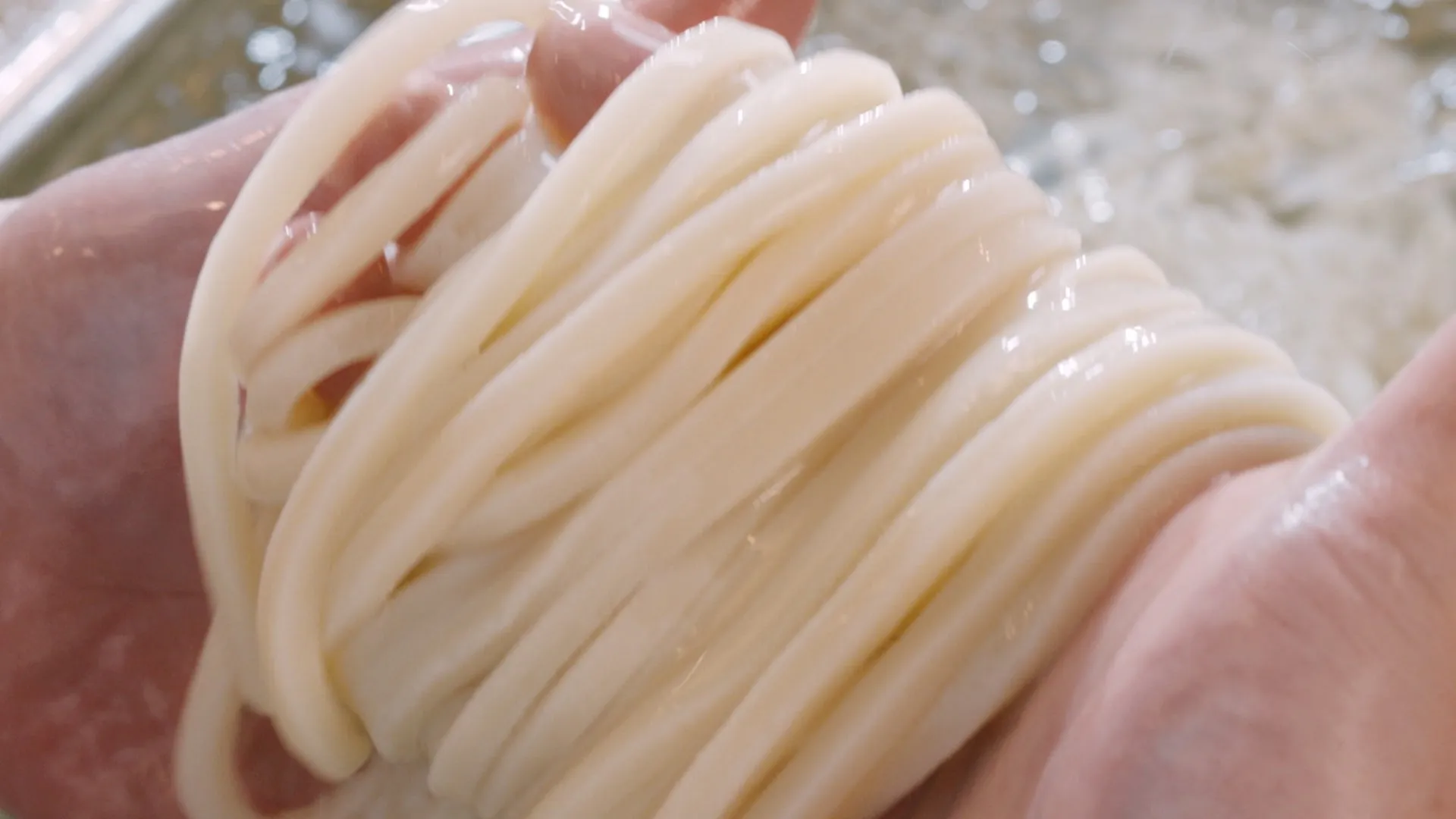 手で持たれたうどんのクローズアップ写真。